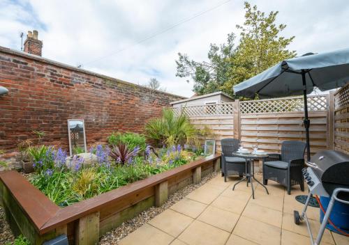 a patio with a brick wall and a table with an umbrella at The Harnser in Beccles