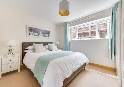 a white bedroom with a bed and a window at The Harnser in Beccles