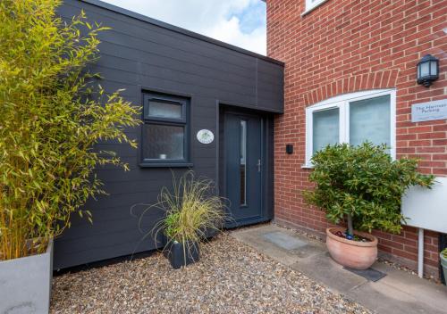 a black front door of a brick house with plants at The Harnser in Beccles