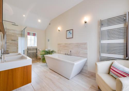 La salle de bains est pourvue d'une grande baignoire blanche et d'un lavabo. dans l'établissement Woodland Lodge, à Wilby