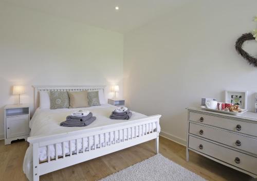 a white bedroom with a white bed and a dresser at The Stables in Friston