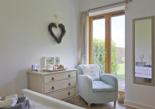 a bedroom with a dresser and a chair and a heart on the wall at The Stables in Friston