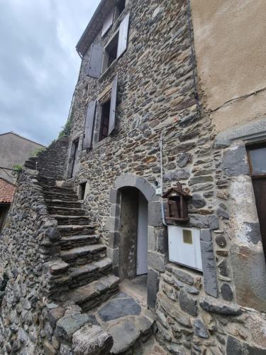 een oud stenen gebouw met een trap naar een deur bij Gîte d'Aigoual in Valleraugue