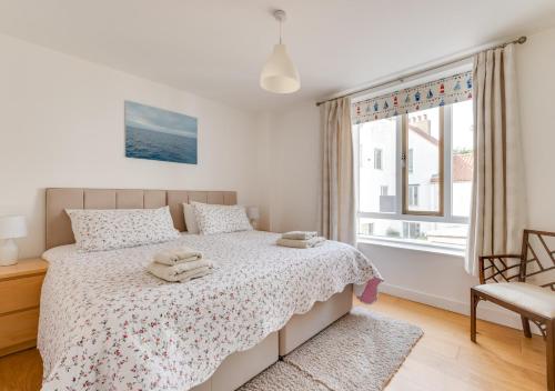 a white bedroom with a bed and a window at Osprey in Southwold