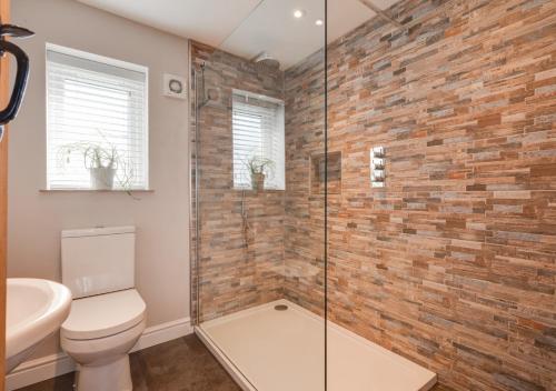 a bathroom with a toilet and a glass shower at Marlborough House Forge in Saxtead