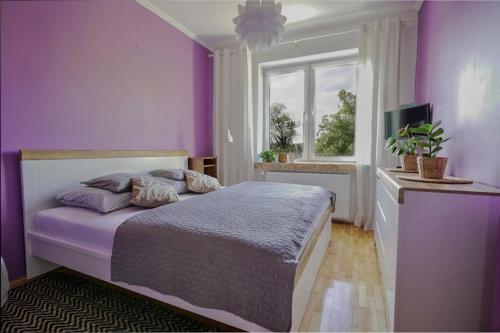 a purple bedroom with a bed and a window at Apartament Dana in Kołobrzeg