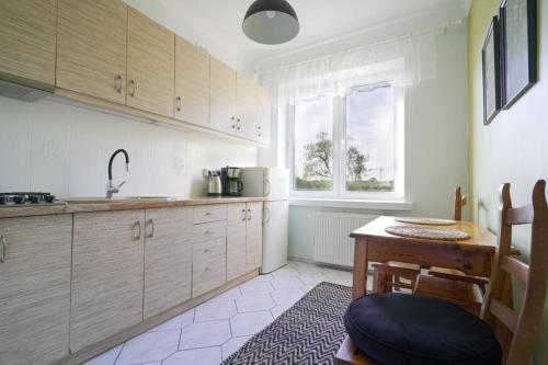 a kitchen with wooden cabinets and a table and a window at Apartament Dana in Kołobrzeg