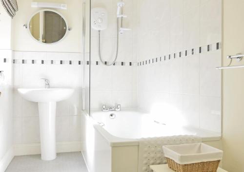 ein weißes Bad mit einem Waschbecken und einer Dusche in der Unterkunft Far View Two in Southwold