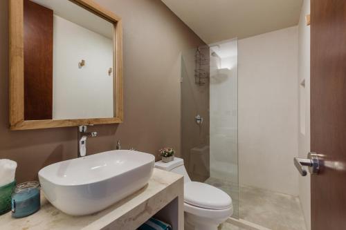 ein Badezimmer mit Waschbecken, Toilette und Spiegel in der Unterkunft Luxury Villas in Aldea Zama in Tulum