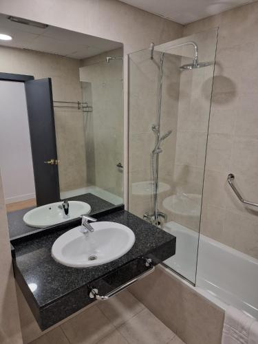 a bathroom with a sink and a glass shower at Micampus Leganés Student Residence in Leganés