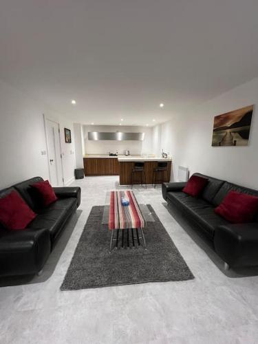 a living room with two black couches and a table at Orion building apartments ,OPOSITE GRAND CENTRAL,FREE CAR PARK in Birmingham