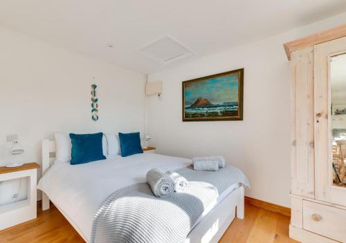two beds in a room with white walls and blue pillows at The Studio in Waldringfield