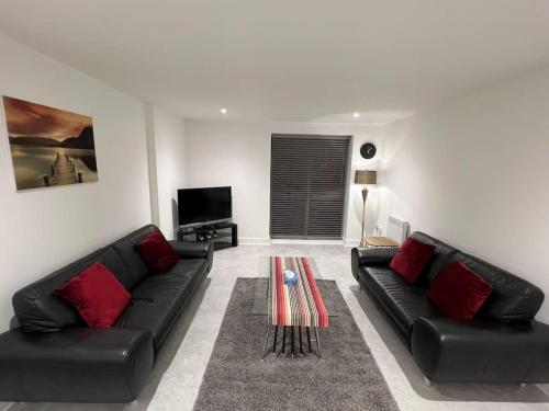 a living room with black leather couches and a table at Orion building apartments ,OPOSITE GRAND CENTRAL,FREE CAR PARK in Birmingham