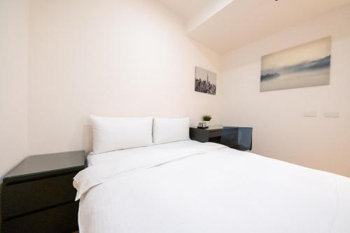 a bedroom with a large white bed and a desk at HotelsHere - Ximen in Taipei