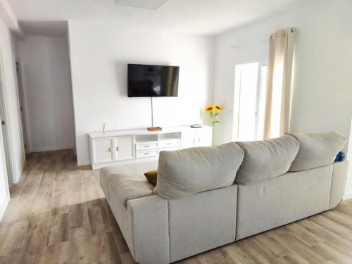 ein weißes Wohnzimmer mit einem Sofa und einem TV in der Unterkunft Apartamento Villa Alpispa in Agüimes