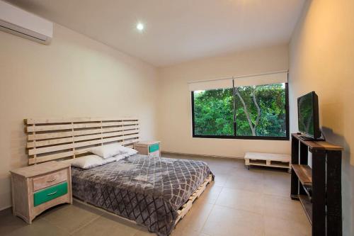 1 dormitorio con cama y ventana grande en Casa Privada en Puerto Morelos, en Puerto Morelos