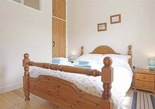 a bedroom with a wooden bed and a wooden dresser at The Tack Room in Wangford