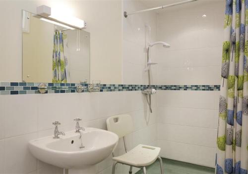 a white bathroom with a sink and a shower at The Tack Room in Wangford