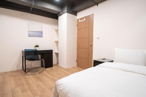 a bedroom with a bed and a desk with a chair at HotelsHere - Ximen in Taipei