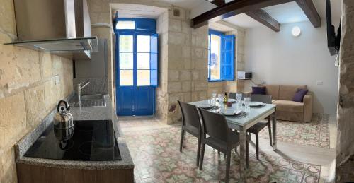 a kitchen with a table and a blue door at Traditional Townhouse In The Hearth Of Valletta in Valletta