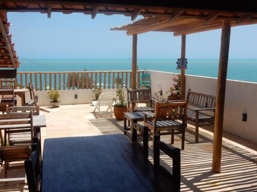 a deck with chairs and tables and a view of the ocean at Pousada Ah Mar in Canoa Quebrada