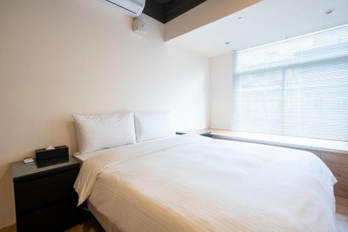 a bedroom with a large white bed and a window at HotelsHere - Ximen in Taipei