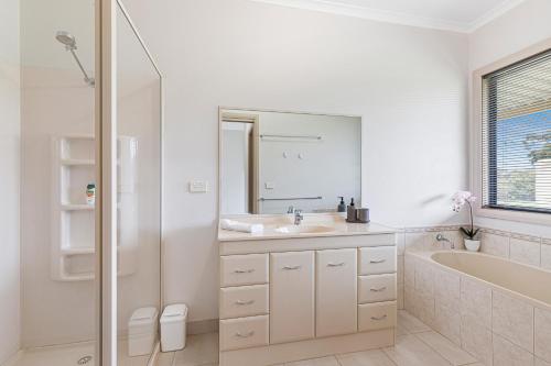 uma casa de banho branca com um lavatório, uma banheira e um espelho. em Morningside farm house with Mountian views... em Wartook