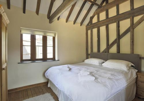Stable Cottage Sternfield في Friston: غرفة نوم بسرير وملاءات بيضاء ونافذة