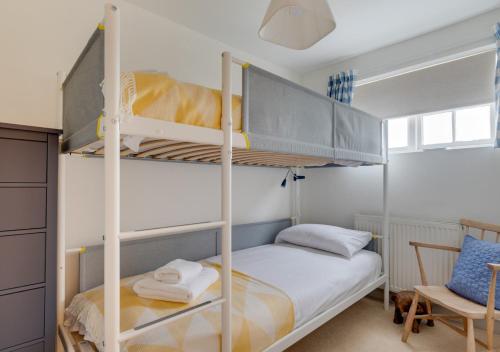 a bedroom with two bunk beds and a chair at Scribblers Cottage in Woodbridge