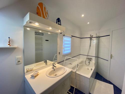 een witte badkamer met 2 wastafels en een spiegel bij Résidence De La Rance in La Richardais