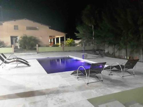 a swimming pool with three chairs around it at night at Casa do sossego in Jijoca de Jericoacoara
