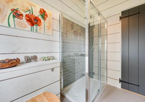 a shower in a bathroom with a glass shower stall at The Cowshed in Crowfield