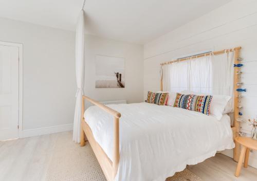 Schlafzimmer mit einem weißen Bett mit einem Kopfteil aus Holz in der Unterkunft The Hideaway in Southwold