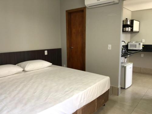 a bedroom with a large bed and a kitchen at Vila Nóbrega Residencial in Foz do Iguaçu