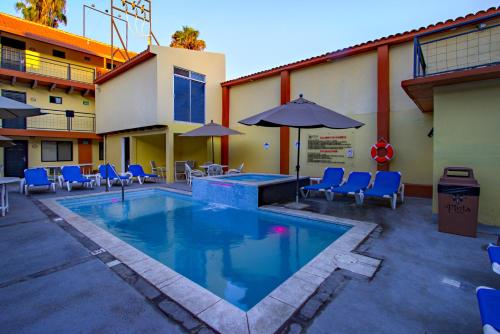 a pool with chairs and umbrellas next to a building at La Pinta Hotel in Ensenada