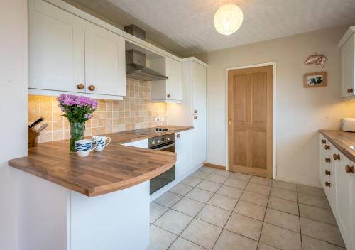 a kitchen with white cabinets and a wooden counter top at 15 Lon Cernyw in Abersoch