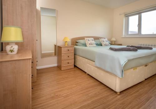 a bedroom with a bed and a dresser and a mirror at 15 Lon Cernyw in Abersoch