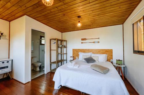 una camera da letto con un letto bianco con un soffitto in legno di Vista para o Mar Dunas e Lagoa em Garopaba a Garopaba