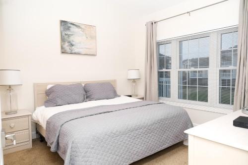 a white bedroom with a bed and a window at Stunning Condo on Golf Course Near Broadway at the Beach in Myrtle Beach