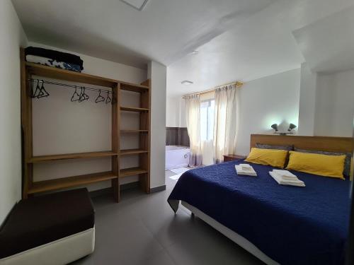 1 dormitorio con 1 cama con colcha azul en Elegante apartamento con vistas al volcán Tungurahua, en Baños