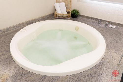 a large white bath tub in a bathroom at Hotel Geranius Ingleses in Florianópolis