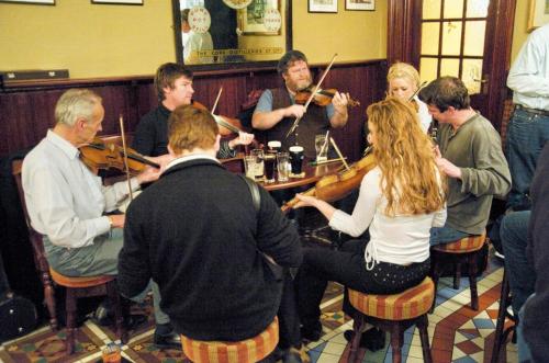 a group of people sitting around a table playingviolin at Blarney Castle Hotel in Blarney