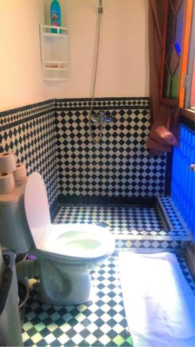 a bathroom with a toilet and a black and white checkered floor at Dar Miouda Fes in Fès