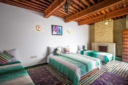 1 dormitorio con 2 camas y chimenea en Dar Miouda Fes, en Fez