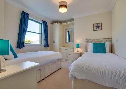 a bedroom with two beds and a desk and a window at 32 St Brides Bay View Apts in Broad Haven