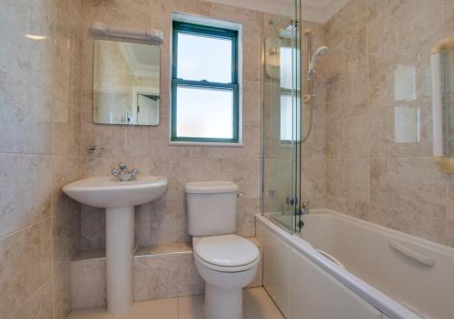 a bathroom with a toilet and a sink and a bath tub at 32 St Brides Bay View Apts in Broad Haven
