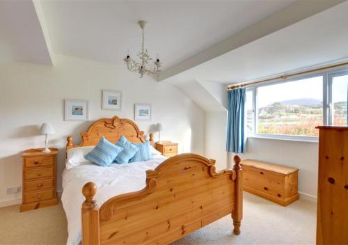a bedroom with a wooden bed and a window at 3 Tyn Llan in Dyffryn