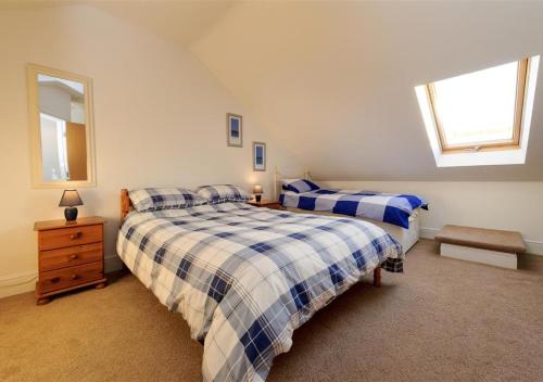 a bedroom with two beds and a dresser and two windows at 5 Afon y Felin in Abersoch