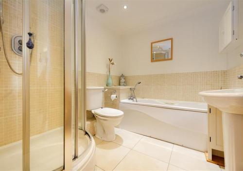a bathroom with a toilet and a tub and a sink at 5 Afon y Felin in Abersoch