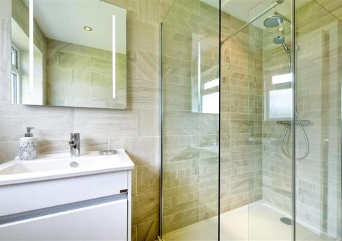 een badkamer met een wastafel en een glazen douche bij 45 Cae Du in Abersoch